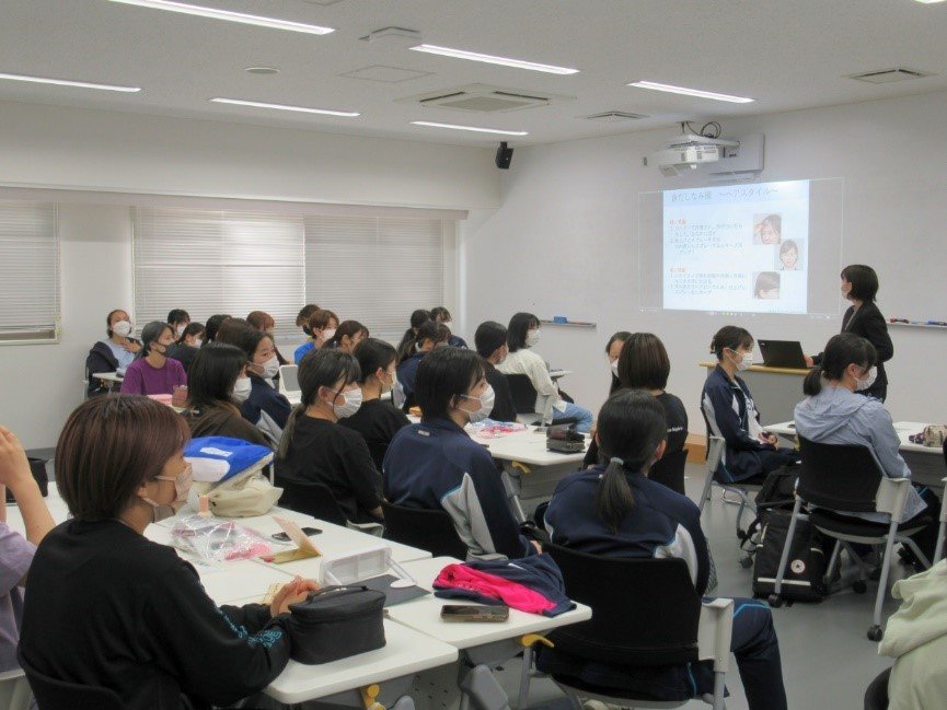 女子学生がグループで座り、ヘアスタイルの解説を受けている様子